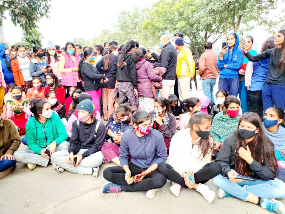 फोटो- विश्वविद्यालय के मुख्य गेट पर धरने पर बैठी छात्राएं।