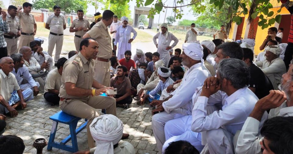 फोटो--गांव भैंसवाल कलां में बिजली अधिकारी और पुलिसकर्मी ग्रामीणों से बातचीत करते हुए।